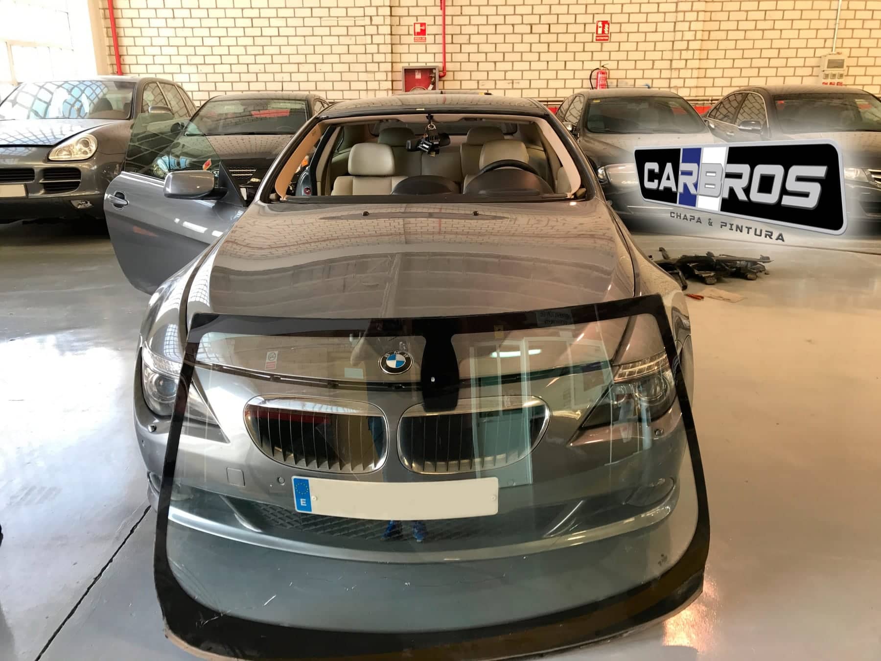 BMW gris de frente, con la luna delantera, en el taller